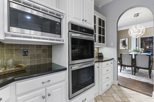 7513 Sugarbush Dr, Garland, TX 75044 - kitchen featuring appliances with stainless steel finishes, crown molding, dark countertops, a chandelier, and white cabinets