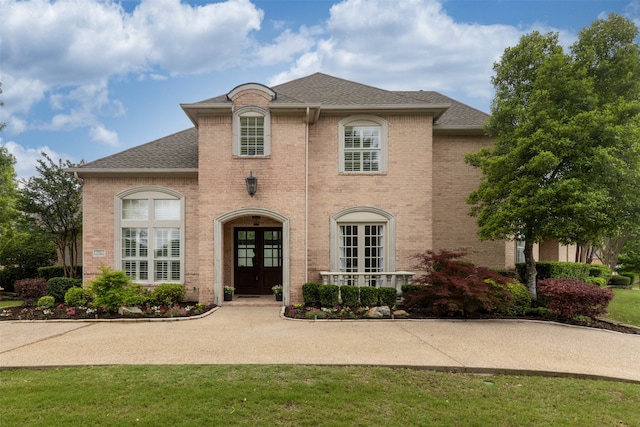 7513 Sugarbush Dr, Garland, TX 75044 - french country style house with french doors, brick siding, a front yard, and roof with shingles