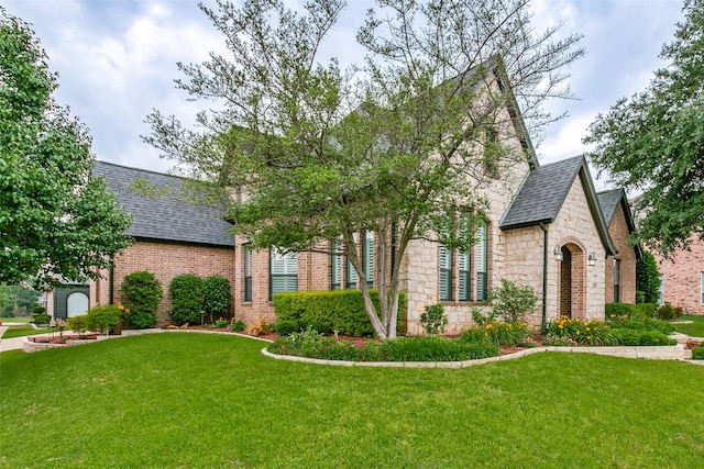 1121 Riverwalk Ct, Colleyville, TX 76034 - english style home featuring roof with shingles, stone siding, a front lawn, and brick siding