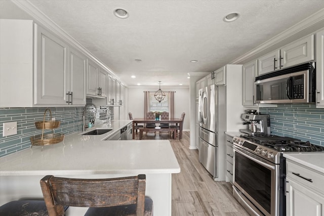 12212 Ridgefair Pl, Farmers Branch, TX 75234 - kitchen featuring appliances with stainless steel finishes, a sink, light countertops, light wood-type flooring, and ornamental molding