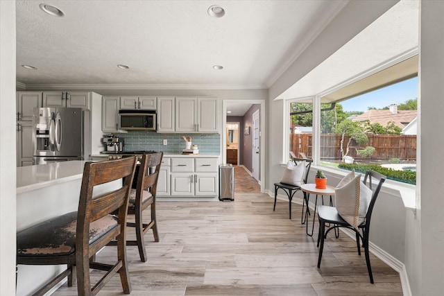 12212 Ridgefair Pl, Farmers Branch, TX 75234 - kitchen with appliances with stainless steel finishes, ornamental molding, light countertops, baseboards, and tasteful backsplash