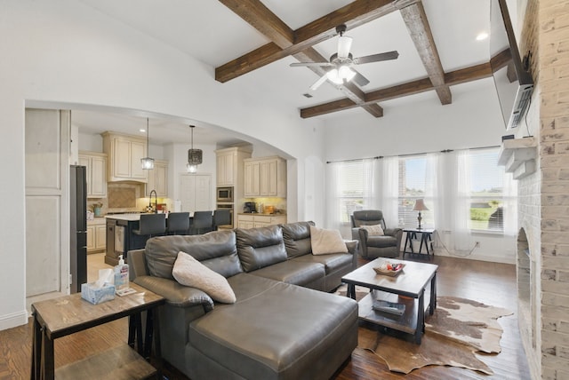 1063 Dominique Dr, Weatherford, TX 76087 - living area featuring arched walkways, beamed ceiling, light wood-style floors, a ceiling fan, and coffered ceiling