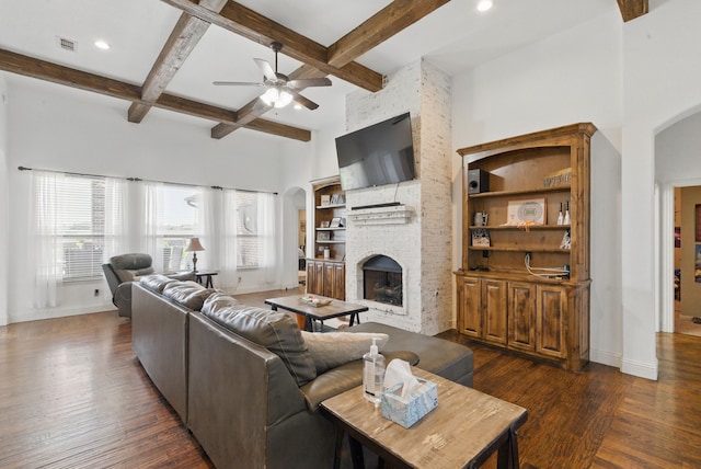 1063 Dominique Dr, Weatherford, TX 76087 - living area featuring arched walkways, ceiling fan, a brick fireplace, dark wood-type flooring, and beamed ceiling