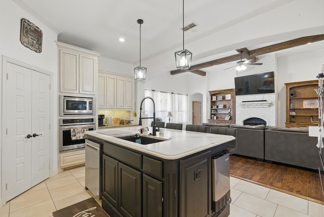 1063 Dominique Dr, Weatherford, TX 76087 - kitchen with appliances with stainless steel finishes, a sink, light tile patterned floors, arched walkways, and ceiling fan