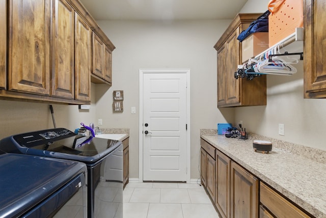 1063 Dominique Dr, Weatherford, TX 76087 - laundry room featuring washing machine and dryer, light tile patterned flooring, cabinet space, and baseboards