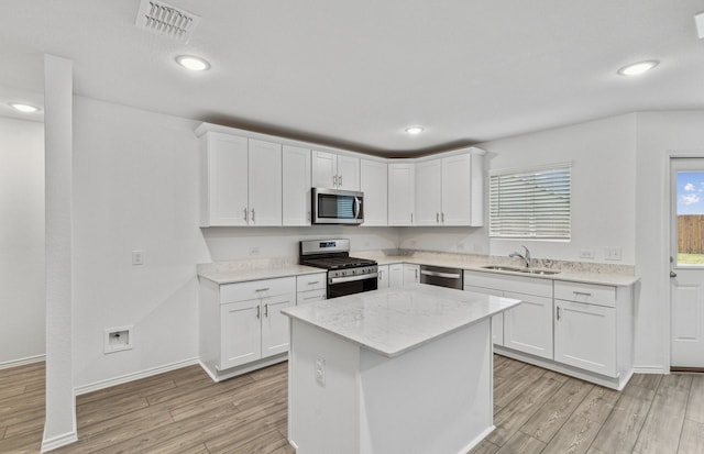 2608 Pecan Park Dr, Denton, TX 76208 - kitchen with appliances with stainless steel finishes, a sink, light wood-type flooring, white cabinetry, and a kitchen island
