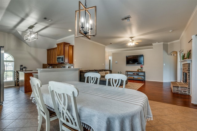 1730 Vista Ridge Dr W, Midlothian, TX 76065 - dining space featuring light tile patterned floors, a ceiling fan, crown molding, lofted ceiling, and a fireplace