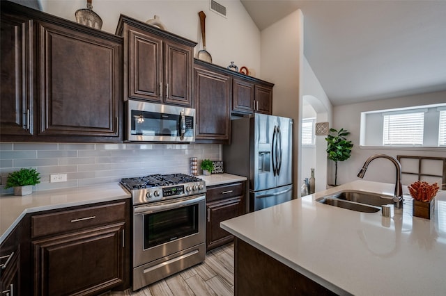 1208 Starlight Ave, Aubrey, TX 76227 - kitchen featuring appliances with stainless steel finishes, a sink, vaulted ceiling, light countertops, and backsplash