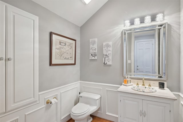 3008 Rosedale Ave, University Park, TX 75205 - bathroom featuring toilet, vanity, a decorative wall, a wainscoted wall, and vaulted ceiling