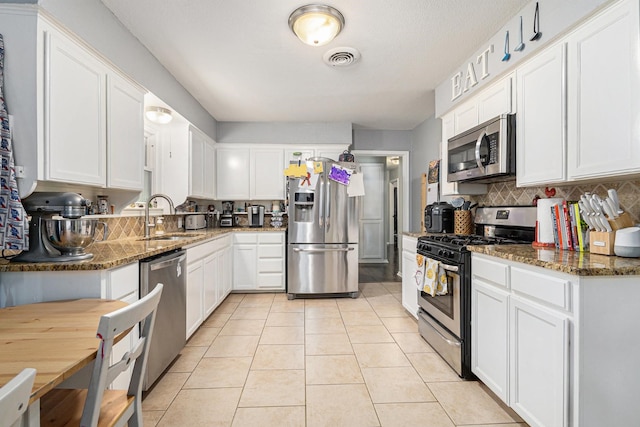 6217 Kentwood Pl, Fort Worth, TX 76112 - kitchen with stainless steel appliances, a sink, white cabinets, backsplash, and dark stone counters