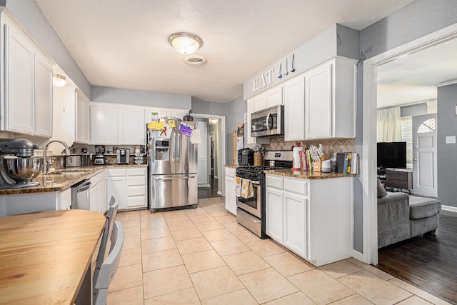 6217 Kentwood Pl, Fort Worth, TX 76112 - kitchen featuring appliances with stainless steel finishes, a sink, white cabinets, and dark stone counters