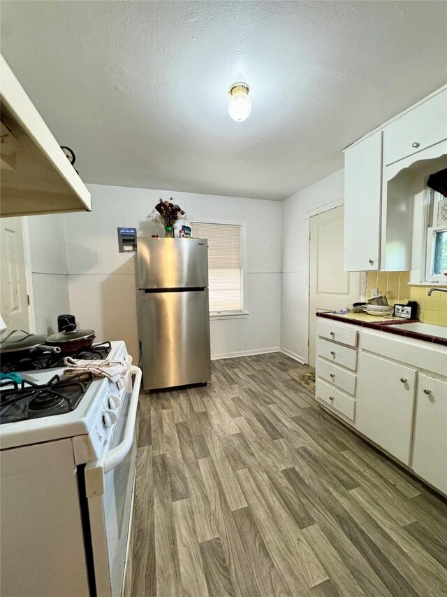 5521 Hightower St, Fort Worth, TX 76112 - kitchen with freestanding refrigerator, gas range gas stove, light wood-style floors, and white cabinets