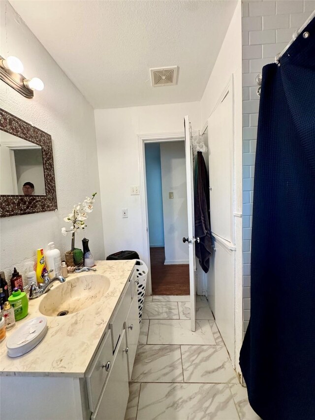 5521 Hightower St, Fort Worth, TX 76112 - bathroom featuring marble look tile flooring, vanity, and a textured ceiling