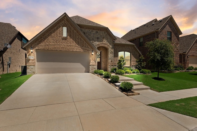 3234 Burke Dr, Royse City, TX 75189 - french country home featuring brick siding, concrete driveway, a lawn, stone siding, and an attached garage