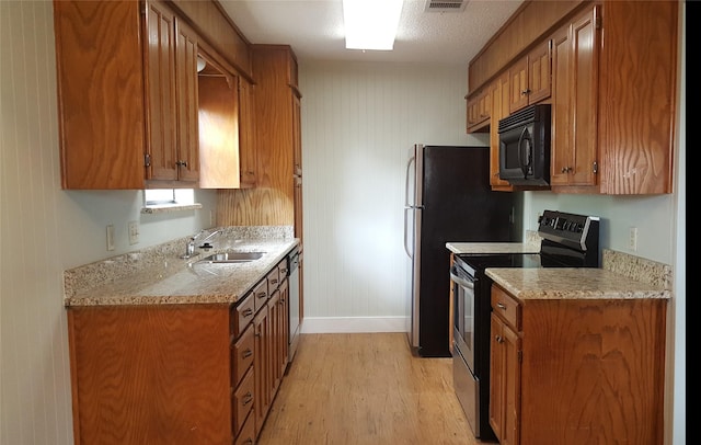 6436 Green Ridge Dr, Watauga, TX 76148 - kitchen with black microwave, stainless steel range with electric cooktop, a sink, brown cabinetry, and light wood finished floors
