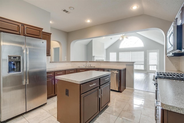 8016 Pretoria Pl, Fort Worth, TX 76123 - kitchen featuring appliances with stainless steel finishes, lofted ceiling, a ceiling fan, a peninsula, and arched walkways