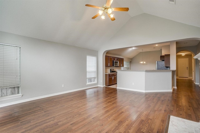 8016 Pretoria Pl, Fort Worth, TX 76123 - unfurnished living room featuring arched walkways, ceiling fan, high vaulted ceiling, wood finished floors, and a chandelier
