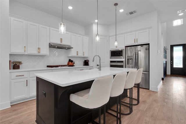 4166 Carter Ct, Denison, TX 75020 - kitchen featuring stainless steel appliances, a sink, under cabinet range hood, light countertops, and white cabinetry
