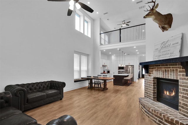 4166 Carter Ct, Denison, TX 75020 - living area featuring a ceiling fan, a brick fireplace, light wood finished floors, a high ceiling, and baseboards