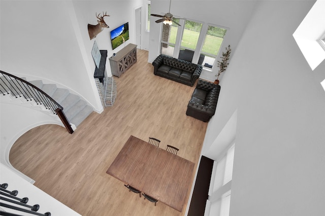4166 Carter Ct, Denison, TX 75020 - living room featuring light wood finished floors, stairway, ceiling fan, a high ceiling, and a fireplace with raised hearth