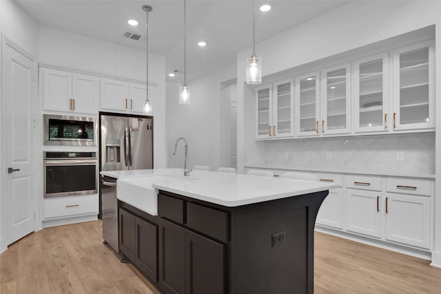 4166 Carter Ct, Denison, TX 75020 - kitchen with stainless steel appliances, white cabinets, light countertops, a sink, and light wood-style flooring