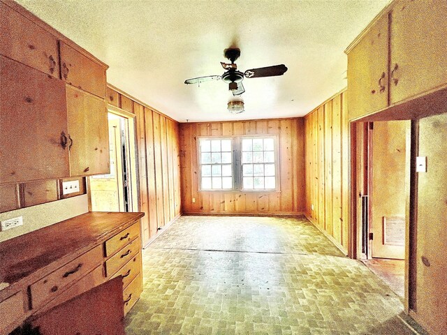 801 W State St, Groesbeck, TX 76642 - kitchen with brick patterned floors, a ceiling fan, wood walls, a textured ceiling, and baseboards