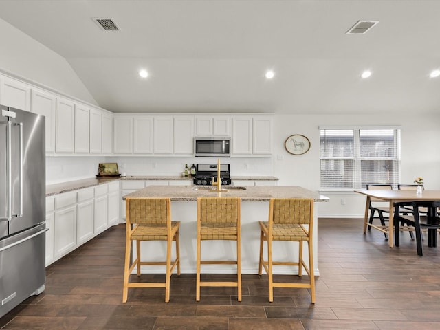 1519 Old Wichita Trl, Saginaw, TX 76131 - kitchen with appliances with stainless steel finishes, a sink, lofted ceiling, dark wood-style floors, and a kitchen breakfast bar