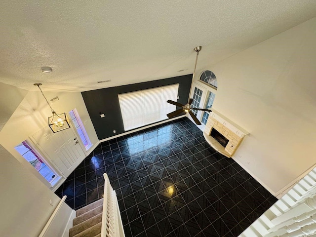 520 Timber Way Dr, Lewisville, TX 75067 - unfurnished living room with a textured ceiling, lofted ceiling, dark tile patterned flooring, a fireplace, and ceiling fan