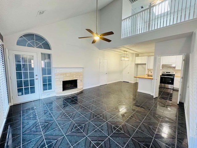 520 Timber Way Dr, Lewisville, TX 75067 - unfurnished living room featuring a high ceiling, a ceiling fan, a sink, baseboards, and a fireplace