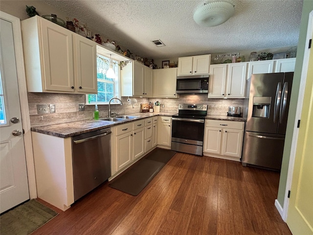 33 County Road 1131, Maud, TX 75567 - kitchen with stainless steel appliances, a sink, dark wood-style floors, backsplash, and a textured ceiling