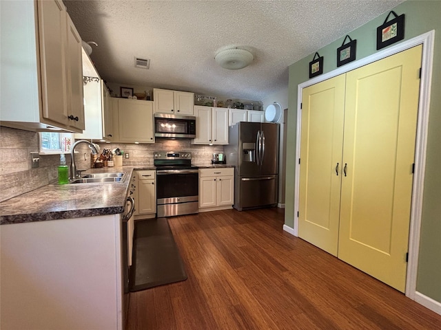 33 County Road 1131, Maud, TX 75567 - kitchen featuring appliances with stainless steel finishes, a sink, dark wood-type flooring, white cabinetry, and backsplash