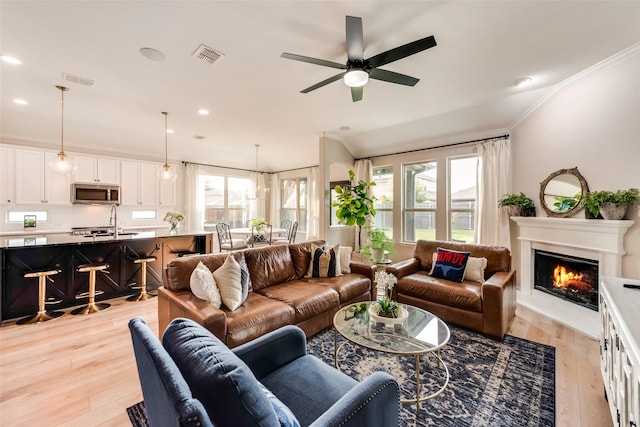 11701 Parade Dr, Frisco, TX 75036 - living room with light wood-style floors, a lit fireplace, ceiling fan, ornamental molding, and recessed lighting