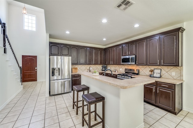 7812 Rancho De La Osa Trl, Mckinney, TX 75070 - kitchen featuring appliances with stainless steel finishes, light countertops, dark brown cabinets, light tile patterned flooring, and decorative backsplash