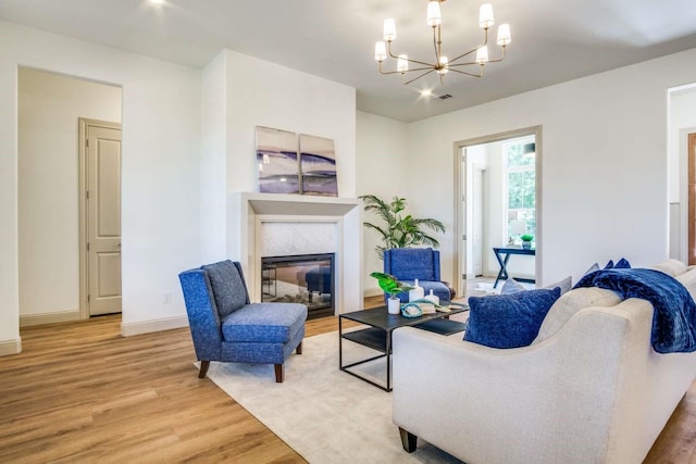 407 Baldwin Dr, Joshua, TX 76058 - living room featuring light wood-style flooring, a chandelier, a glass covered fireplace, and baseboards