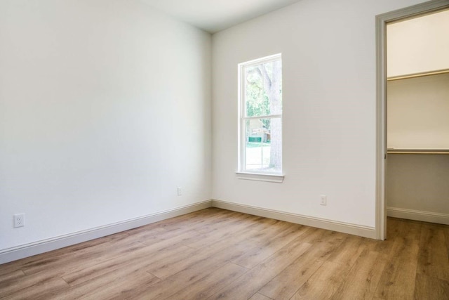 407 Baldwin Dr, Joshua, TX 76058 - unfurnished bedroom featuring a walk in closet, light wood-style floors, multiple windows, and a closet