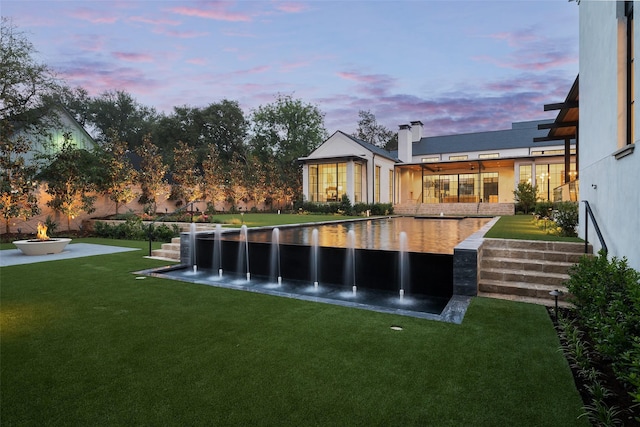 5531 Walnut Hill Ln, Dallas, TX 75229 - back of house at dusk with a fire pit, a lawn, a patio, and stucco siding