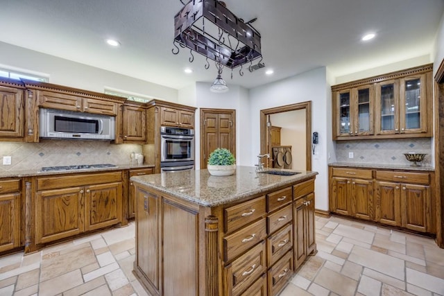 87 Eagle Chase Ln, Pottsboro, TX 75076 - kitchen with stainless steel appliances, a sink, brown cabinets, a center island, and tasteful backsplash