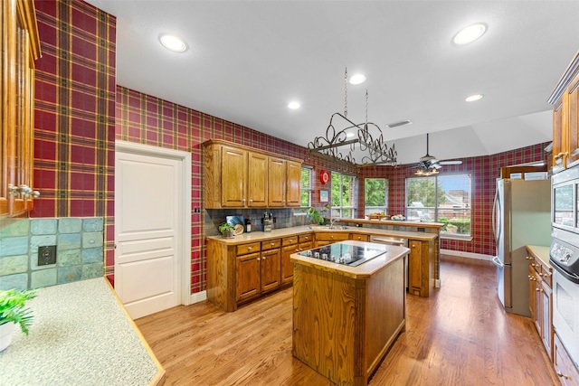 1621 Grandberry Dr, Melissa, TX 75454 - kitchen with wallpapered walls, a center island, brown cabinets, appliances with stainless steel finishes, and a peninsula
