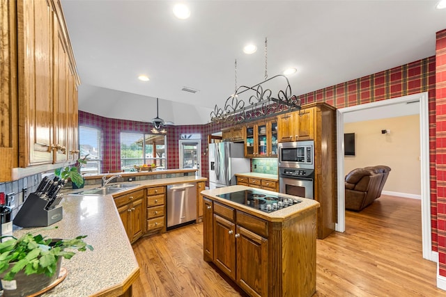 1621 Grandberry Dr, Melissa, TX 75454 - kitchen with stainless steel appliances, a sink, wallpapered walls, brown cabinetry, and a center island