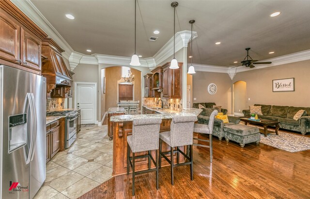 171 Lori Dr, Stonewall, LA 71078 - kitchen with arched walkways, stainless steel appliances, light stone countertops, ceiling fan, and a kitchen bar