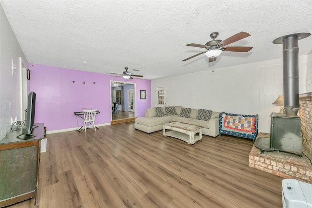 309 School House Rd, Paradise, TX 76073 - living room featuring a wood stove, a ceiling fan, a textured ceiling, wood finished floors, and baseboards