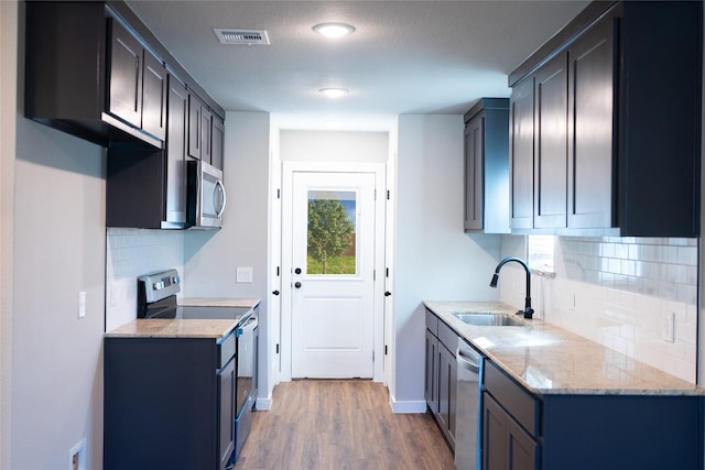 2404 Miller St, Denison, TX 75020 - kitchen featuring stainless steel appliances, a sink, wood finished floors, and light stone countertops