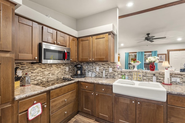 123 Little River Bnd, Mabank, TX 75156 - kitchen featuring stainless steel microwave, black electric stovetop, a ceiling fan, a sink, and tasteful backsplash