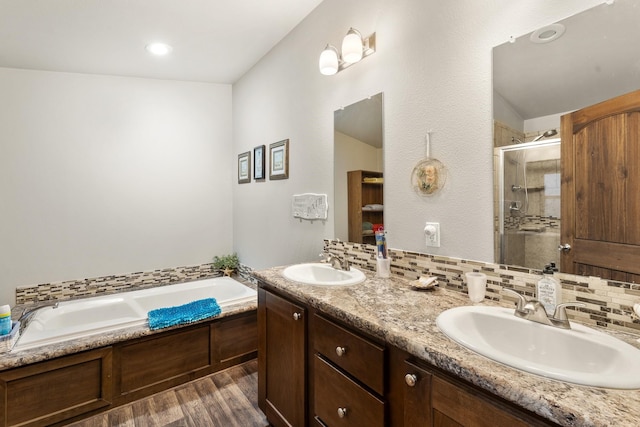 123 Little River Bnd, Mabank, TX 75156 - full bath featuring wood finished floors, a stall shower, a bath, backsplash, and double vanity