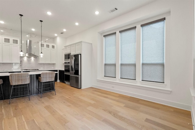1812 Welker Dr, Van Alstyne, TX 75495 - kitchen featuring appliances with stainless steel finishes, wall chimney exhaust hood, light countertops, white cabinetry, and light wood-style flooring