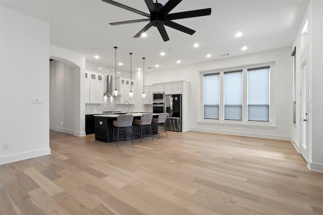 1812 Welker Dr, Van Alstyne, TX 75495 - kitchen with appliances with stainless steel finishes, arched walkways, a breakfast bar, a ceiling fan, and a kitchen island with sink