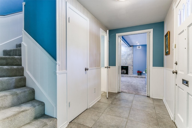 907 Glen Dell Dr, Irving, TX 75061 - entryway with a decorative wall, stairway, light tile patterned floors, wainscoting, and light colored carpet