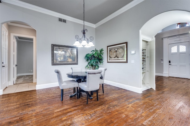 11626 Capitan Ln, Frisco, TX 75033 - dining space with arched walkways, a chandelier, crown molding, wood finished floors, and baseboards