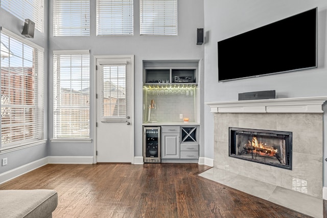 2433 Mallard Dr, Little Elm, TX 75068 - unfurnished living room featuring wine cooler, dark wood-style floors, a dry bar, baseboards, and a tile fireplace