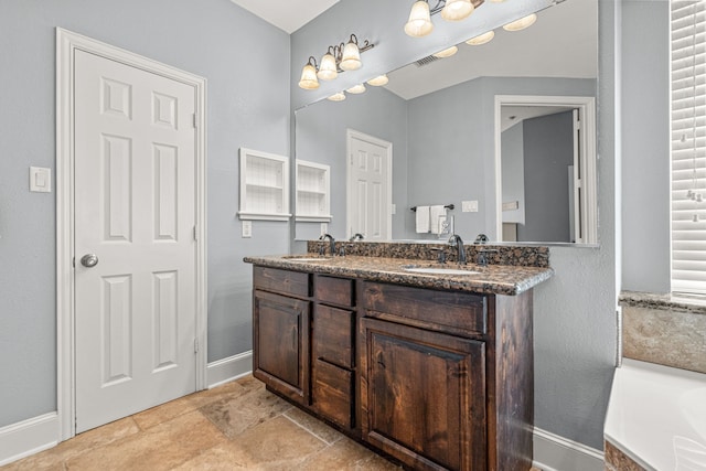 2433 Mallard Dr, Little Elm, TX 75068 - bathroom with baseboards, stone finish floors, double vanity, and a bath